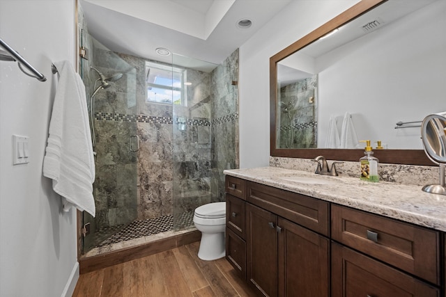 bathroom featuring visible vents, toilet, a shower stall, vanity, and wood finished floors