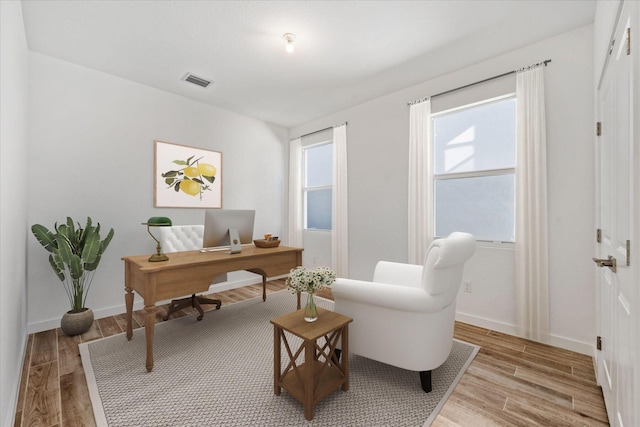 home office featuring light wood-type flooring, visible vents, and baseboards