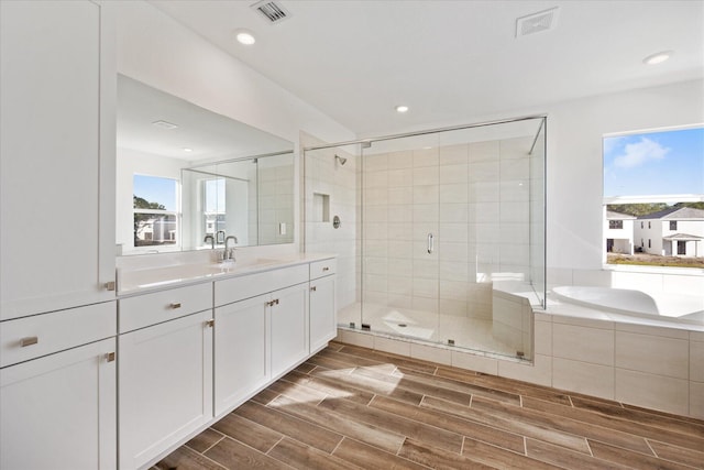 full bathroom featuring vanity, visible vents, wood finish floors, recessed lighting, and a shower stall