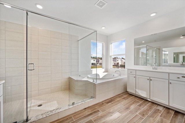 full bath with visible vents, a shower stall, wood finish floors, a garden tub, and vanity