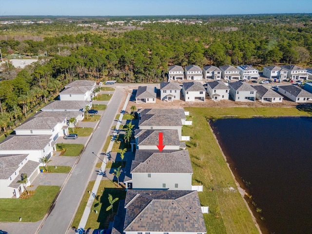 drone / aerial view featuring a forest view, a residential view, and a water view