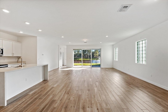 unfurnished living room featuring recessed lighting, visible vents, light wood-style flooring, and a sink