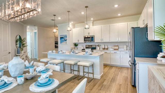 kitchen featuring appliances with stainless steel finishes, a breakfast bar area, white cabinets, light wood finished floors, and light countertops