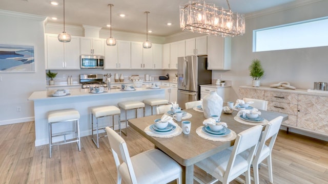 dining space featuring a chandelier, light wood-type flooring, baseboards, and ornamental molding