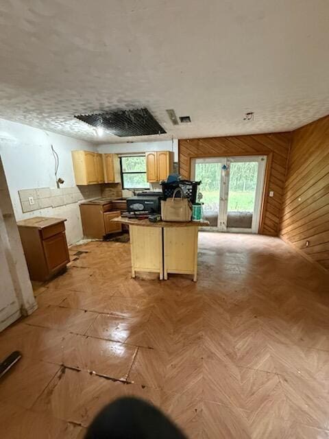 kitchen featuring dark countertops, wooden walls, a kitchen island, and a kitchen breakfast bar