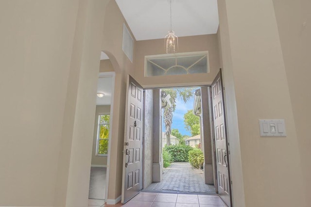 6731 Southport Dr W, Boynton Beach, FL 33472 - foyer featuring a notable chandelier, light tile patterned floors, baseboards, arched walkways, and a towering ceiling