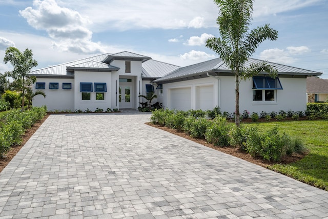 prairie-style home with decorative driveway, stucco siding, a standing seam roof, metal roof, and a garage