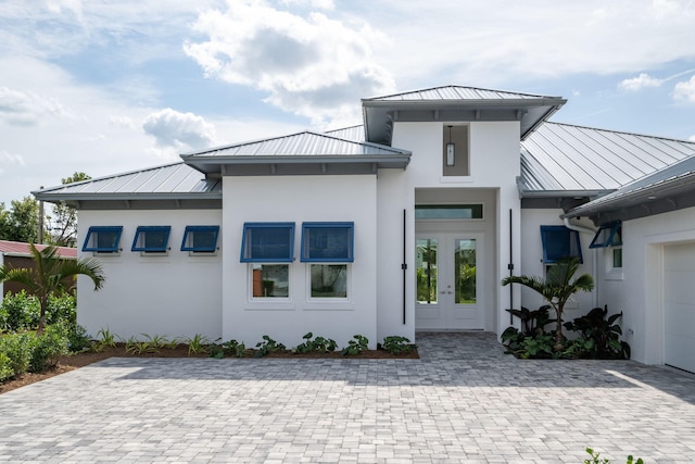 view of front of property with metal roof, french doors, a standing seam roof, and stucco siding