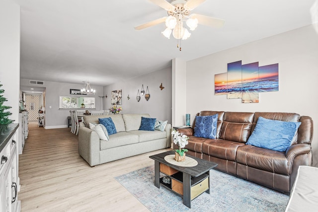 living room featuring ceiling fan with notable chandelier and light hardwood / wood-style flooring