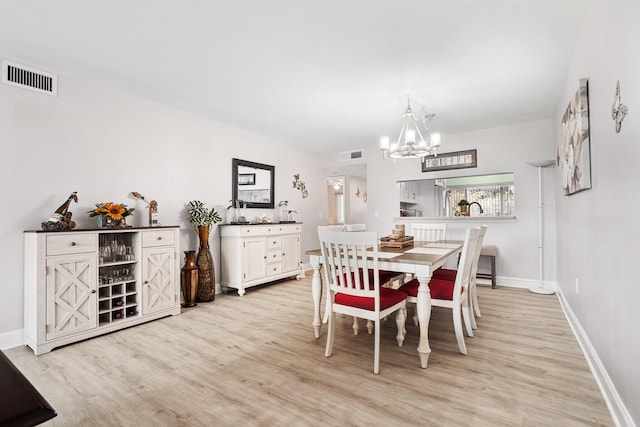 dining space with light hardwood / wood-style flooring and a chandelier