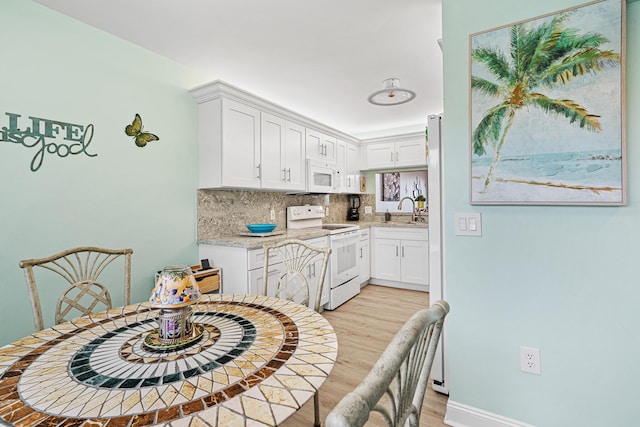 kitchen featuring white cabinetry, white appliances, light hardwood / wood-style floors, and backsplash