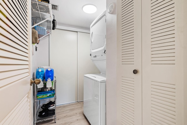 laundry area with stacked washer and dryer and light wood-type flooring