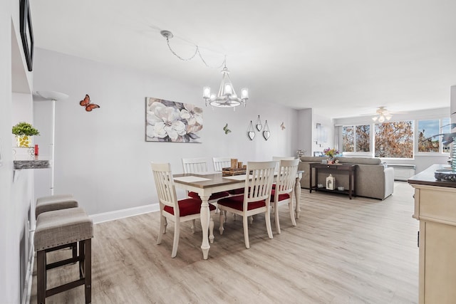 dining space with ceiling fan with notable chandelier and light hardwood / wood-style floors