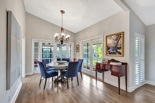 dining room with high vaulted ceiling, french doors, a chandelier, and light wood-type flooring