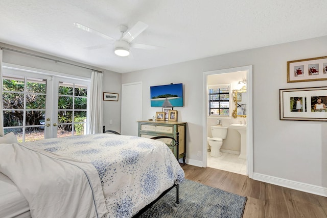 bedroom with hardwood / wood-style flooring, ensuite bath, multiple windows, and french doors