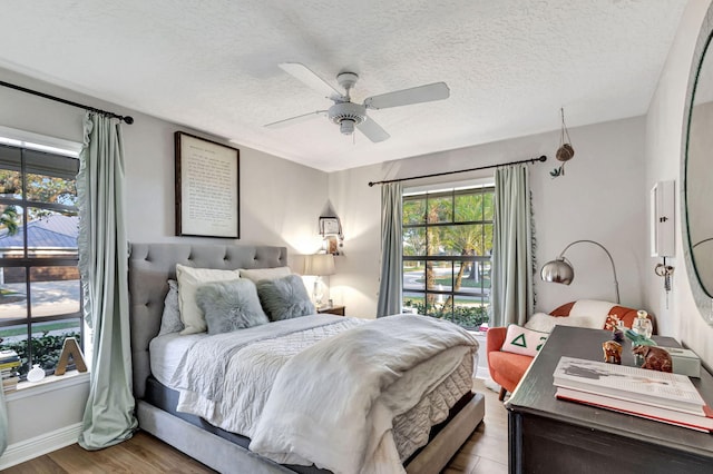 bedroom with hardwood / wood-style floors, a textured ceiling, and ceiling fan