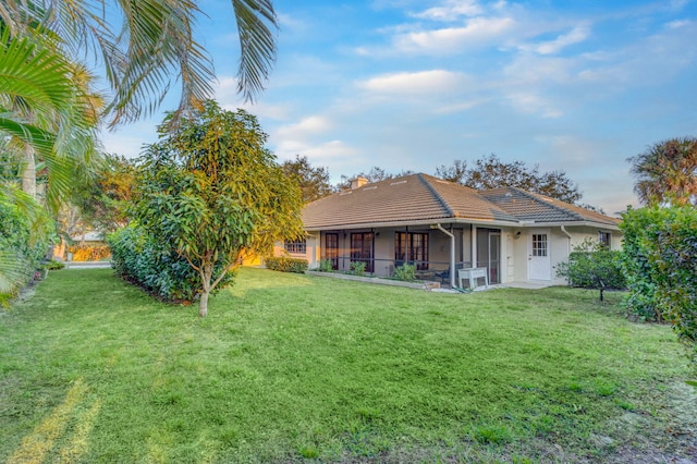 rear view of house featuring a sunroom and a yard