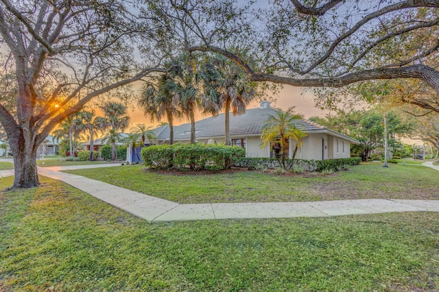 property exterior at dusk featuring a lawn