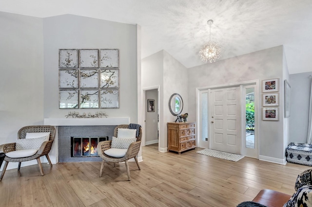 foyer featuring high vaulted ceiling, light hardwood / wood-style flooring, and a notable chandelier