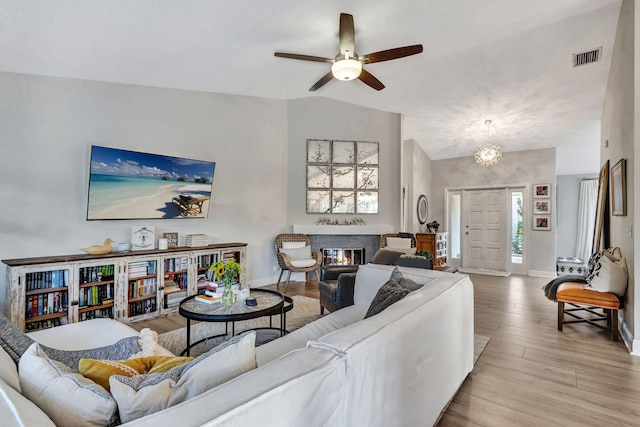 living room featuring ceiling fan, lofted ceiling, and light hardwood / wood-style flooring