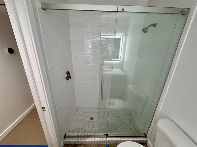 bathroom with toilet and a shower with door