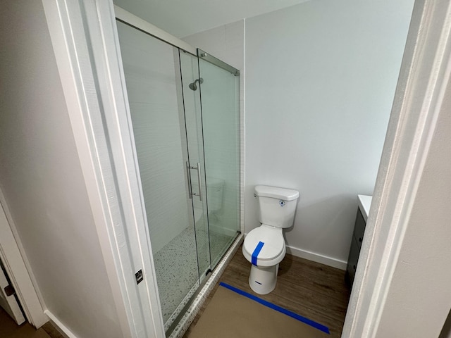 bathroom featuring a shower with shower door, hardwood / wood-style floors, and toilet