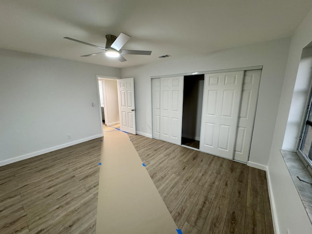 unfurnished bedroom featuring ceiling fan, hardwood / wood-style floors, and a closet