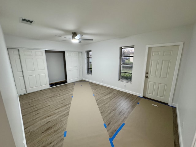 unfurnished bedroom with wood-type flooring, ceiling fan, and a closet