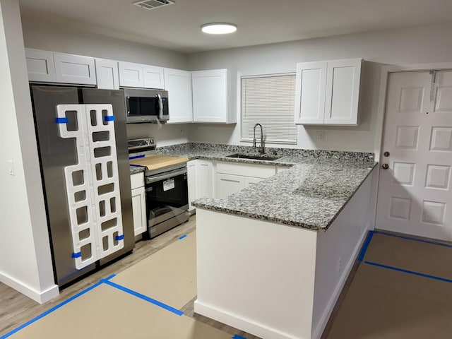 kitchen featuring sink, stainless steel appliances, white cabinets, and stone counters