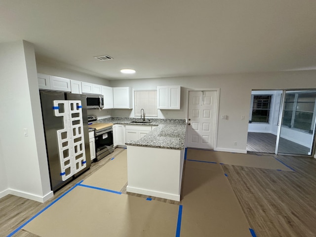 kitchen featuring sink, light wood-type flooring, stone counters, stainless steel appliances, and white cabinets