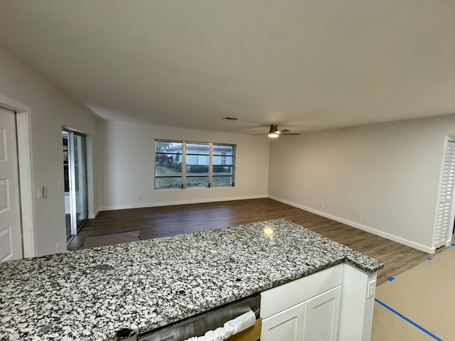 kitchen featuring stone countertops, dark hardwood / wood-style floors, white cabinets, stainless steel dishwasher, and ceiling fan