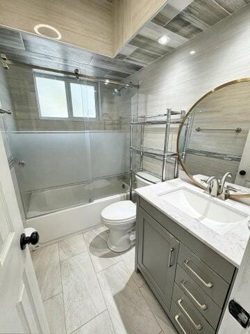 full bathroom with enclosed tub / shower combo, vanity, and toilet