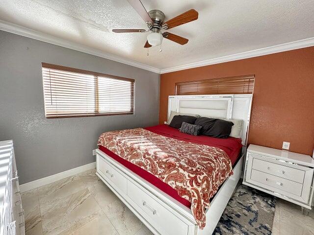 bedroom featuring crown molding, ceiling fan, and a textured ceiling