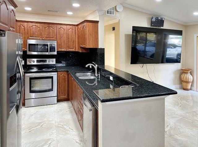 kitchen with appliances with stainless steel finishes, sink, dark stone countertops, and kitchen peninsula