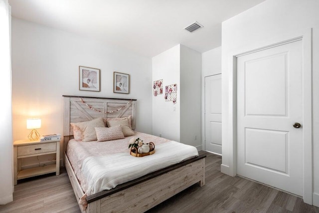 bedroom with light wood finished floors and visible vents