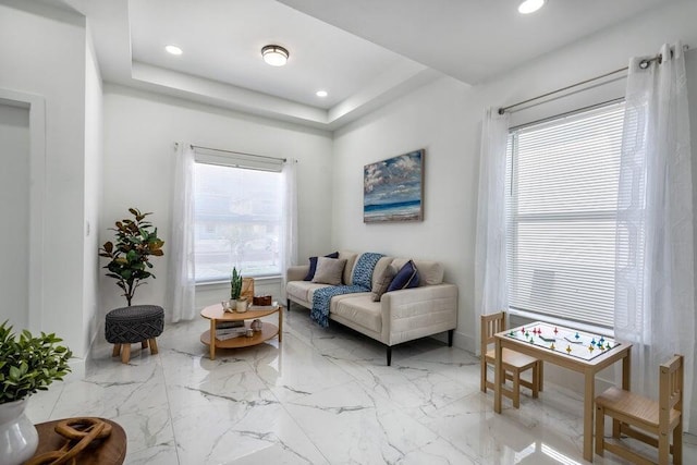 living room featuring a tray ceiling, plenty of natural light, recessed lighting, and marble finish floor