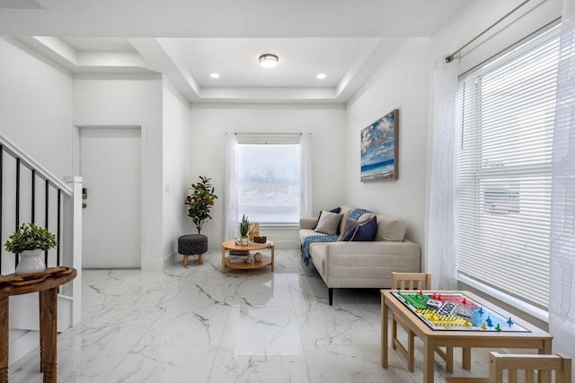 living area featuring recessed lighting, a raised ceiling, plenty of natural light, and stairs