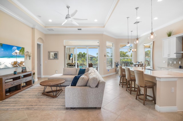 tiled living room featuring ornamental molding, sink, and a tray ceiling