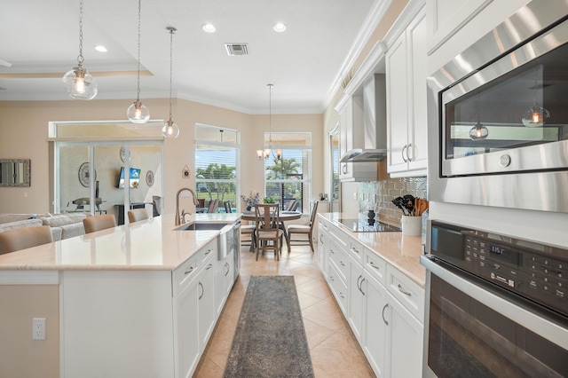 kitchen with a kitchen island with sink, white cabinetry, and appliances with stainless steel finishes