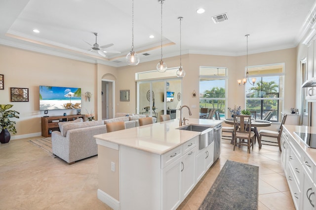 kitchen featuring sink, white cabinetry, hanging light fixtures, a center island with sink, and a raised ceiling