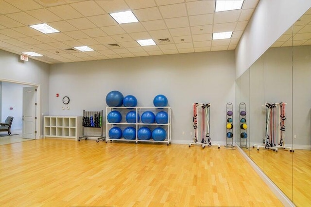 exercise area with hardwood / wood-style flooring, a towering ceiling, and a drop ceiling