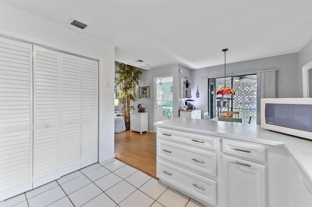 kitchen featuring light tile patterned floors, hanging light fixtures, and white cabinets