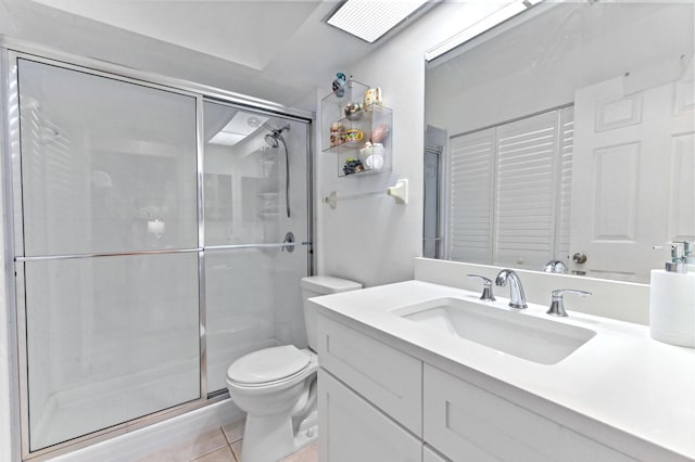 bathroom with tile patterned flooring, vanity, a shower with door, and toilet