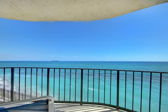 balcony featuring a view of the beach and a water view