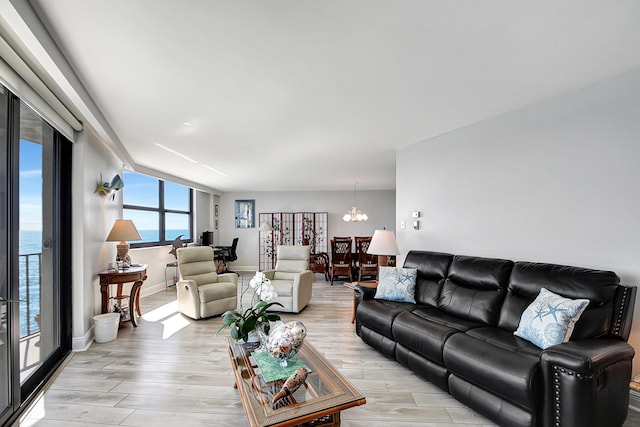 living room with a water view, a notable chandelier, and light hardwood / wood-style floors