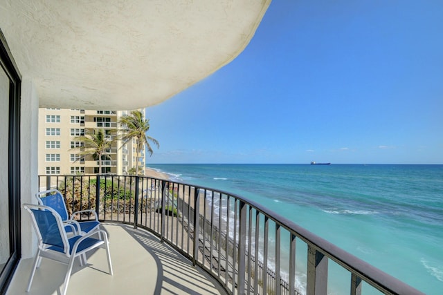 balcony with a water view and a view of the beach