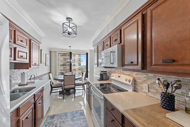 kitchen with a chandelier, hanging light fixtures, light tile patterned floors, ornamental molding, and white appliances