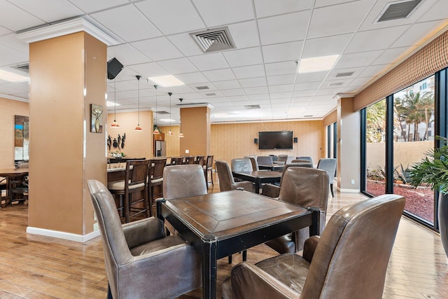 dining space with light hardwood / wood-style flooring and a paneled ceiling