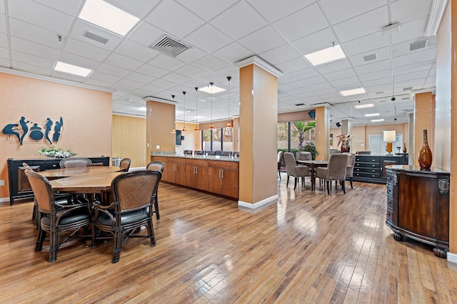 dining area featuring a drop ceiling and light hardwood / wood-style floors