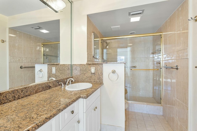 2871 N Ocean Blvd Unit F427, Boca Raton, FL 33431 - full bathroom featuring a stall shower, tile patterned flooring, vanity, toilet, and tile walls